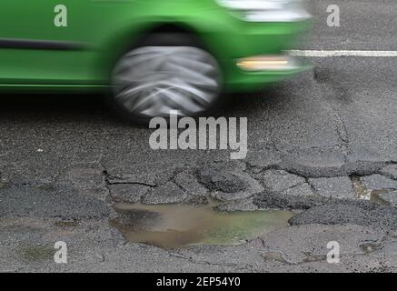 26 febbraio 2021, Brandeburgo, Francoforte (Oder): Un'automobile guida su una strada piena di buche. L'inverno non è ancora finito, ma il cambio di gelo e di rugiada finora ha probabilmente avuto un forte impatto sulle strade del Brandeburgo. Questo è il timore dell'agenzia statale per la circolazione stradale e dei comuni responsabili, ma non sono ancora in grado di redigere un bilancio dei danni. Foto: Patrick Pleul/dpa-Zentralbild/ZB Foto Stock