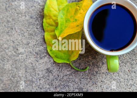 Tazza di caffè vista dall'alto con foglie autunnali su cemento pavimento Foto Stock
