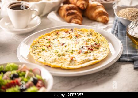 Frittata fresca servita su un piatto cosparso di peperoncino e coriandolo tritati, servita con assortimento di cibi per la colazione e caffè Foto Stock