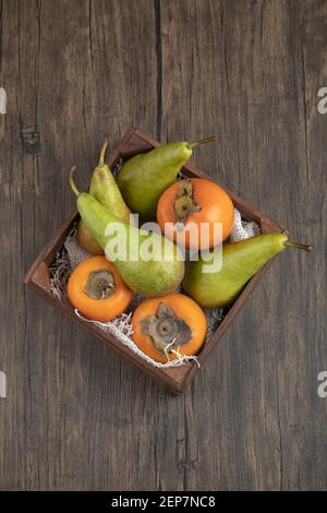 Deliziosi persimmons fuyu e pere mature in scatola di legno Foto Stock