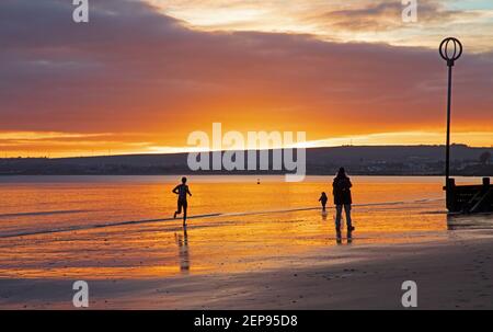 Portobello, Edimburgo, Scozia. Meteo nel Regno Unito. 27 febbraio 2021. Spettacolare alba sul mare Firth of Forth. In questo ultimo fine settimana d'inverno la temperatura è di 5 gradi C. goduto da escursionisti e joggers. Foto Stock