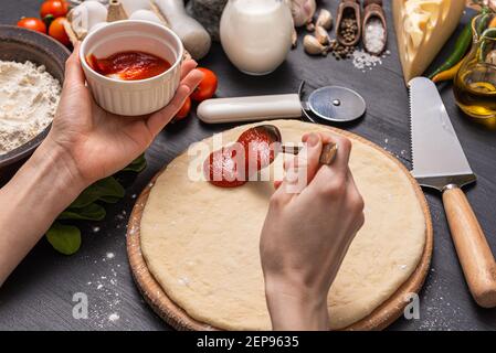 Pizza classica margherita con formaggio a forma di cuore. Preparazione di una cena di gala a fasi per due a casa in onore del giorno di San Valentino. Foto Stock