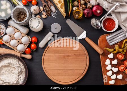 Pizza classica margherita con formaggio a forma di cuore. Preparazione di una cena di gala a fasi per due a casa in onore del giorno di San Valentino. Foto Stock