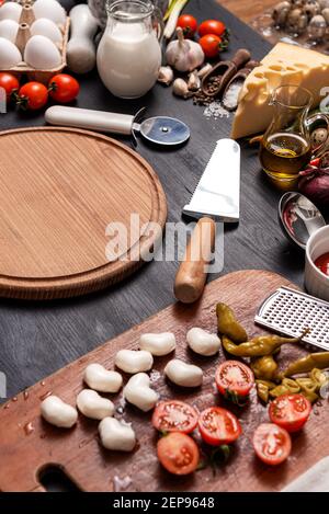 Pizza classica margherita con formaggio a forma di cuore. Preparazione di una cena di gala a fasi per due a casa in onore del giorno di San Valentino. Foto Stock