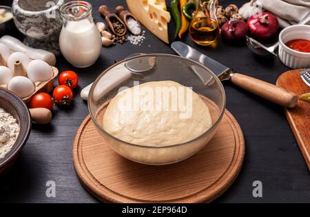 Pizza classica margherita con formaggio a forma di cuore. Preparazione di una cena di gala a fasi per due a casa in onore del giorno di San Valentino. Foto Stock
