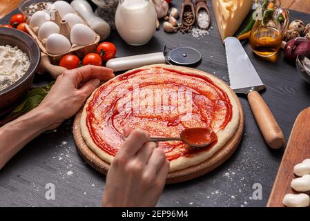 Pizza classica margherita con formaggio a forma di cuore. Preparazione di una cena di gala a fasi per due a casa in onore del giorno di San Valentino. Foto Stock