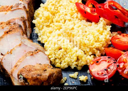 Bistecca di carne appetitosa con porridge di bulgur e verdure Foto Stock