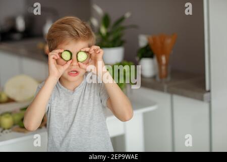 Il bambino mette le verdure sul tavolo e prepara un'insalata. Foto Stock