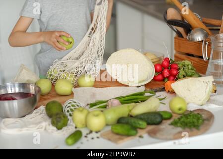 Il bambino mette le verdure sul tavolo e prepara un'insalata. Foto Stock