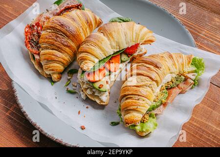 Il concetto di una ricca e gustosa colazione di croissant classici freschi con una varietà di condimenti da ricotta jamon avocado, fragole, essiccati al sole Foto Stock