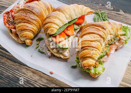 Il concetto di una ricca e gustosa colazione di croissant classici freschi con una varietà di condimenti da ricotta jamon avocado, fragole, essiccati al sole Foto Stock