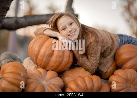 Una ragazza si trova su un trolley con zucche mature Foto Stock