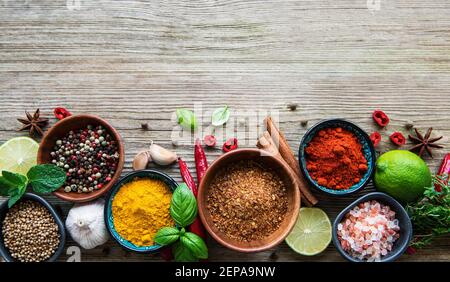 Una selezione di varie spezie colorate su di un tavolo di legno in ciotole Foto Stock