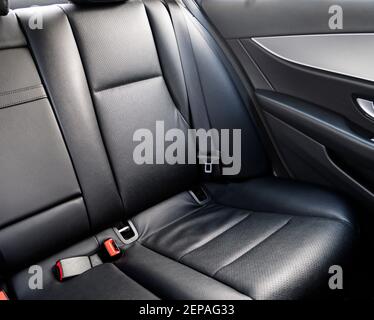 Sedili posteriori in pelle nera per passeggeri in un'auto di lusso moderna. Pelle nera traforata con cuciture. Auto all'interno. Comodi sedili rossi in pelle. Auto inter Foto Stock