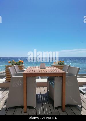 Tavolo da pranzo con sedie in rattan all'aperto contro il mare. Foto Stock