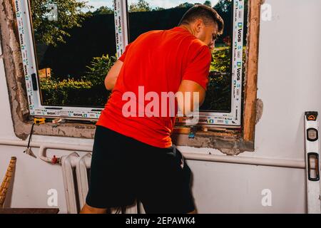 Dolyna, Ucraina 31 luglio 2020: Un dipendente installa un telaio per finestre, installando una finestra in plastica. Foto Stock