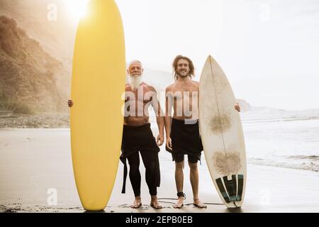 Amici multigenerali divertirsi mentre si surfing sulla spiaggia - Focus sulle facce Foto Stock