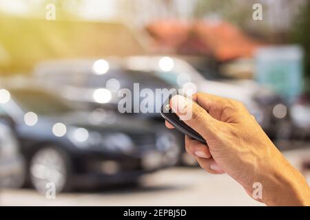 Gli uomini premono le mani sui sistemi di allarme per auto con telecomando con luce solare Foto Stock