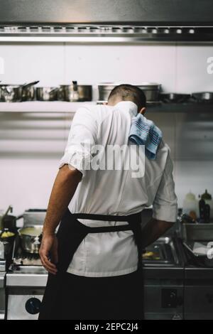 Ritratto di uno chef maschile che cucina all'indietro in una cucina ristorante. Foto Stock