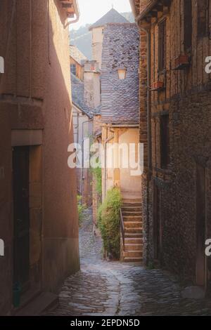 Un vicolo di campagna nel pittoresco e affascinante borgo medievale francese di Conques, Aveyron, una popolare destinazione turistica estiva nella regione delle Occitanie Foto Stock