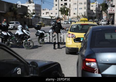 Hebron. 27 Feb 2021. Un agente di polizia lavora in un checkpoint nella città di Hebron, in Cisgiordania, il 27 febbraio 2021. I Governatori di Betlemme e Hebron hanno annunciato la chiusura dei due governatori della Cisgiordania meridionale per 48 ore a partire dalle 12:00 venerdì a causa dell'aumento del numero di infezioni da COVID-19. Credit: Mamoun Wazwaz/Xinhua/Alamy Live News Foto Stock