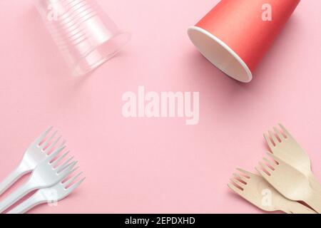 utensili da cucina ecologici e plastici modello o telaio. cucchiai e forcelle in legno su fondo corallino rosa Foto Stock