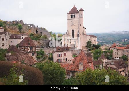 Il borgo medievale francese in cima alla collina di Saint-Cirq-Lapopie e la sua chiesa fortificata del 16 ° secolo nella Valle del Lot, Francia. Foto Stock