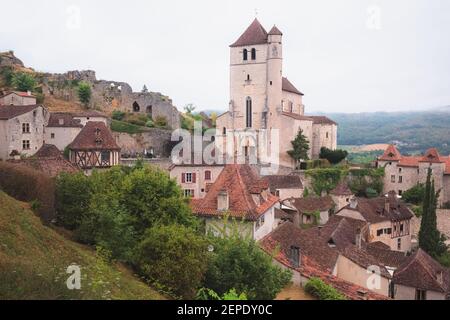 Il borgo medievale francese in cima alla collina di Saint-Cirq-Lapopie e la sua chiesa fortificata del 16 ° secolo nella Valle del Lot, Francia. Foto Stock