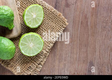 Primo piano di bergamotto fresco e fetta di bergamotto su sfondo di tavola di legno scuro. Bergamotto su vecchio marrone di legno con spazio di copia. (Bergamotto o lime Kaffir) Foto Stock