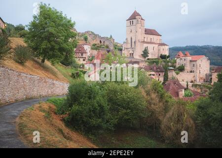 Il borgo medievale francese in cima alla collina di Saint-Cirq-Lapopie e la sua chiesa fortificata del 16 ° secolo nella Valle del Lot, Francia. Foto Stock