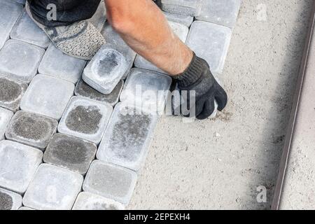 lavoratore installare nuovi mattoni o blocco di lastra a pathway. piastrelle di pavimentazione per le riparazioni stradali Foto Stock