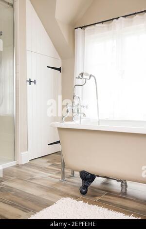 Interni bagno dal design retrò con vasca da bagno con roll top in ghisa, vasca da bagno con piede di artiglio o a zampa. Bagni contemporanei e lussuosi con piastrelle, Regno Unito Foto Stock