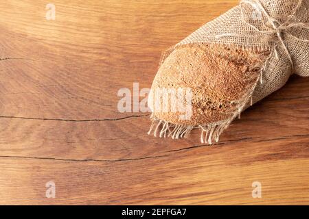 Pane fatto in casa appena sfornato con crusca su fondo di legno e burlap e con un salice sprig. Foodphoto. Foto di alta qualità Foto Stock