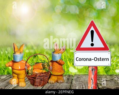 Cartello di avvertimento di Pasqua a Corona con coniglietti pasquali in giardino in tedesco Foto Stock