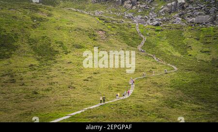 Persone che camminano sul lungomare di legno, salendo su scale e scale al Monte Cuilcagh. Ripida montagna con massi e macerie, Irlanda del Nord Foto Stock