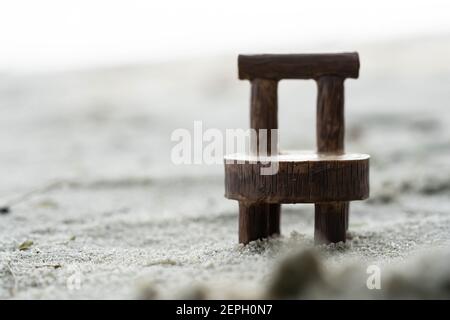 Poltroncina in legno macro shot su sabbia. Sedia marrone su sabbia primo piano shot Foto Stock