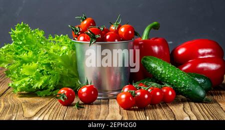 Set di verdure per insalata, cetrioli, peperoni, pomodori ciliegini rossi freschi su un tavolo di legno vista superiore. Laterale. Vendemmia. Cibo naturale. Foto Stock