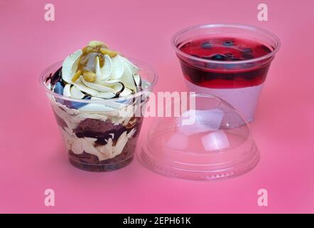 Dessert con cioccolato e bacche in tazze di plastica. Dessert con crema e cioccolato e frutta di cagliata con gelatina. Dessert da asporto in disparte Foto Stock