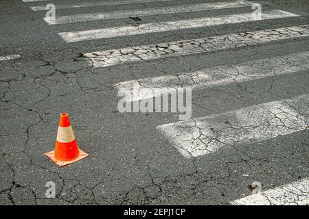 Cono di traffico di due colori situato in una strada della città ruvida Foto Stock