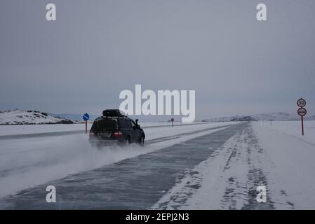 Olchon, Russia. 25 Feb 2021. Le auto guidano su uno strato di ghiaccio spesso un metro del lago Baikal all'isola di Olkhon. Un segnale stradale indica che il limite di velocità sul ghiaccio sul lato ovest del lago è 30. Credit: Ulf Maider/dpa/Alamy Live News Foto Stock