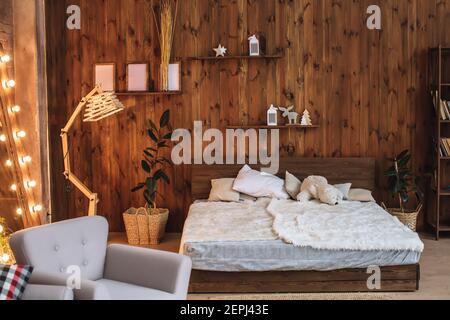 Luminoso interno della camera da letto con pareti in legno, un letto in legno con interni in mansarda bianchi nel monolocale Foto Stock