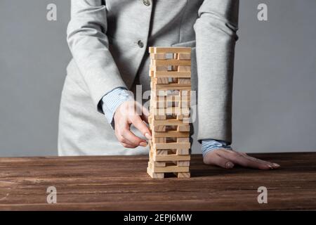 Uomo d'affari che rimuove il blocco di legno dalla torre Foto Stock