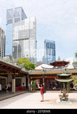 Un adoratore prega nel cortile centrale del tempio cinese Thian Hock Tien, situato tra moderni edifici residenziali nel quartiere di Chinatown, in centro Foto Stock