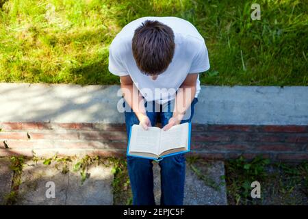 Young Man ha letto un libro nel Summer Park Foto Stock