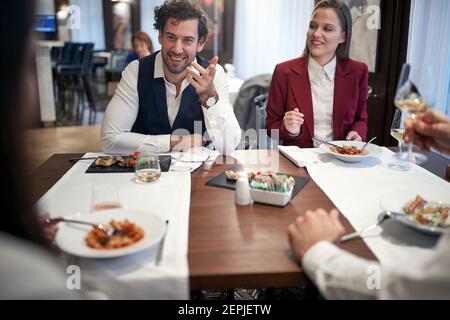 Giovani uomini d'affari che hanno una piacevole conversazione in un'atmosfera allegra durante un pranzo al ristorante. Business, ristorante, pranzo Foto Stock