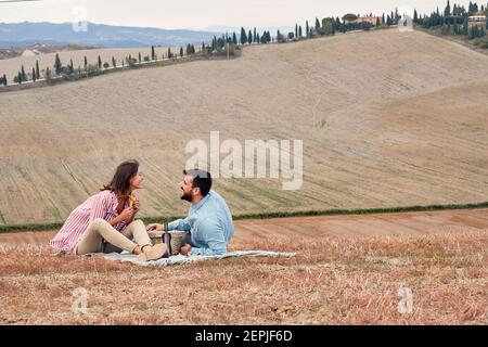 Una giovane coppia gode di un picnic in un'atmosfera rilassata su un grande prato. Amore, relazione, pic-nic, insieme Foto Stock