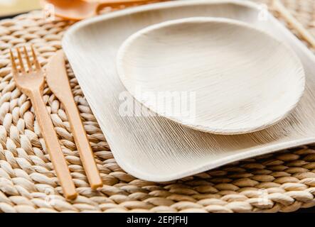 Set di nuove piastre a balestra di palma vuote biodegradabili a secco e forchetta, coltello, cucchiaio e paglia di bambù commestibile. Stoviglie perfette per le feste in giardino. Foto Stock