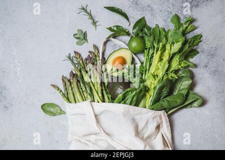 Ingredienti alimentari sani verdure verdi e frutta in sacchetto di lino ecologico, zero rifiuti e concetto di consumo pulito. Sfondo grigio Foto Stock