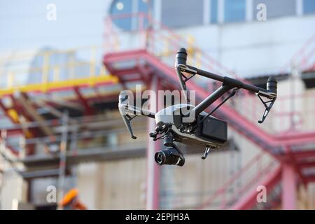 Quadricottero nero con potente fotocamera per una costruzione iindustriale sfocata. Ispezione visiva nell'industria. Foto Stock