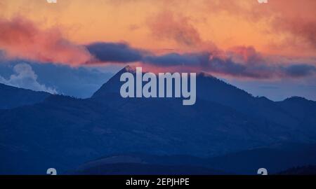 Una vista sul vulcano Costa Rica tra le nuvole, illuminato dal sole che tramonta. Foresta di Quetzal dopo il tramonto. Parco Nazionale Los Quetzales Riserva Naturale. Costo Foto Stock